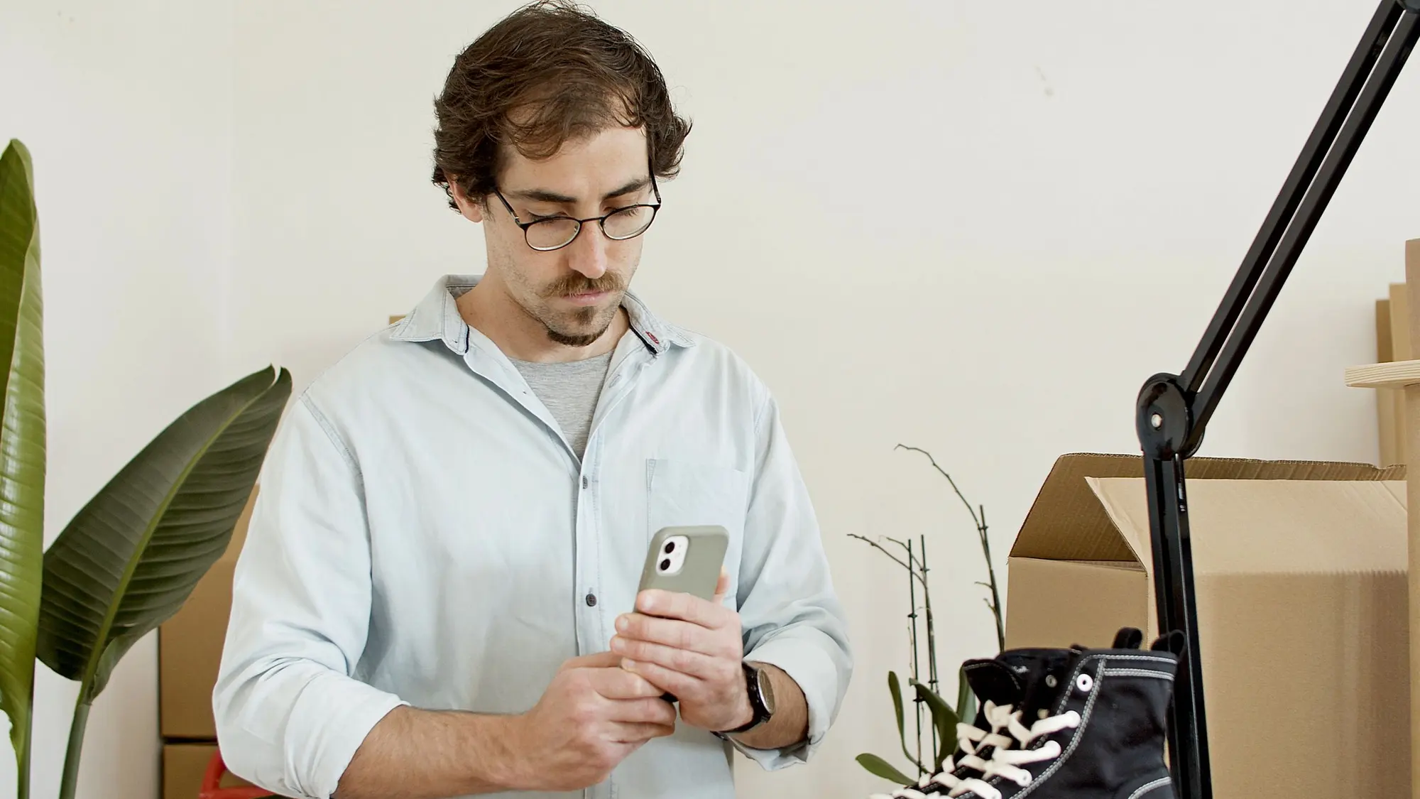 Ein Ladeninhaber steht in seinem Geschäft und schaut auf sein Smartphone.