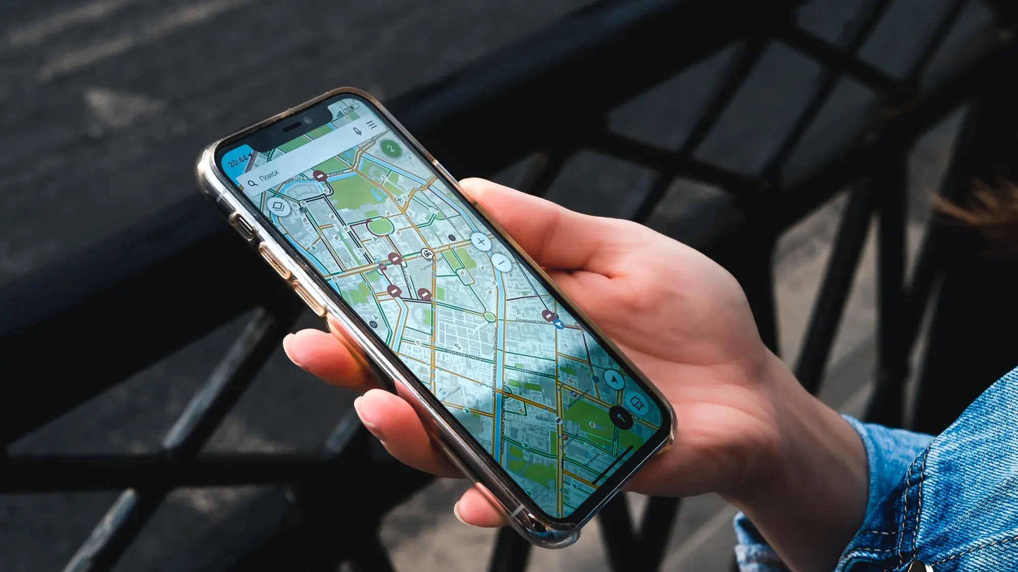 Eine Hand hält ein Smartphone, auf dem eine Kartenansicht der Umgebung zu sehen ist.